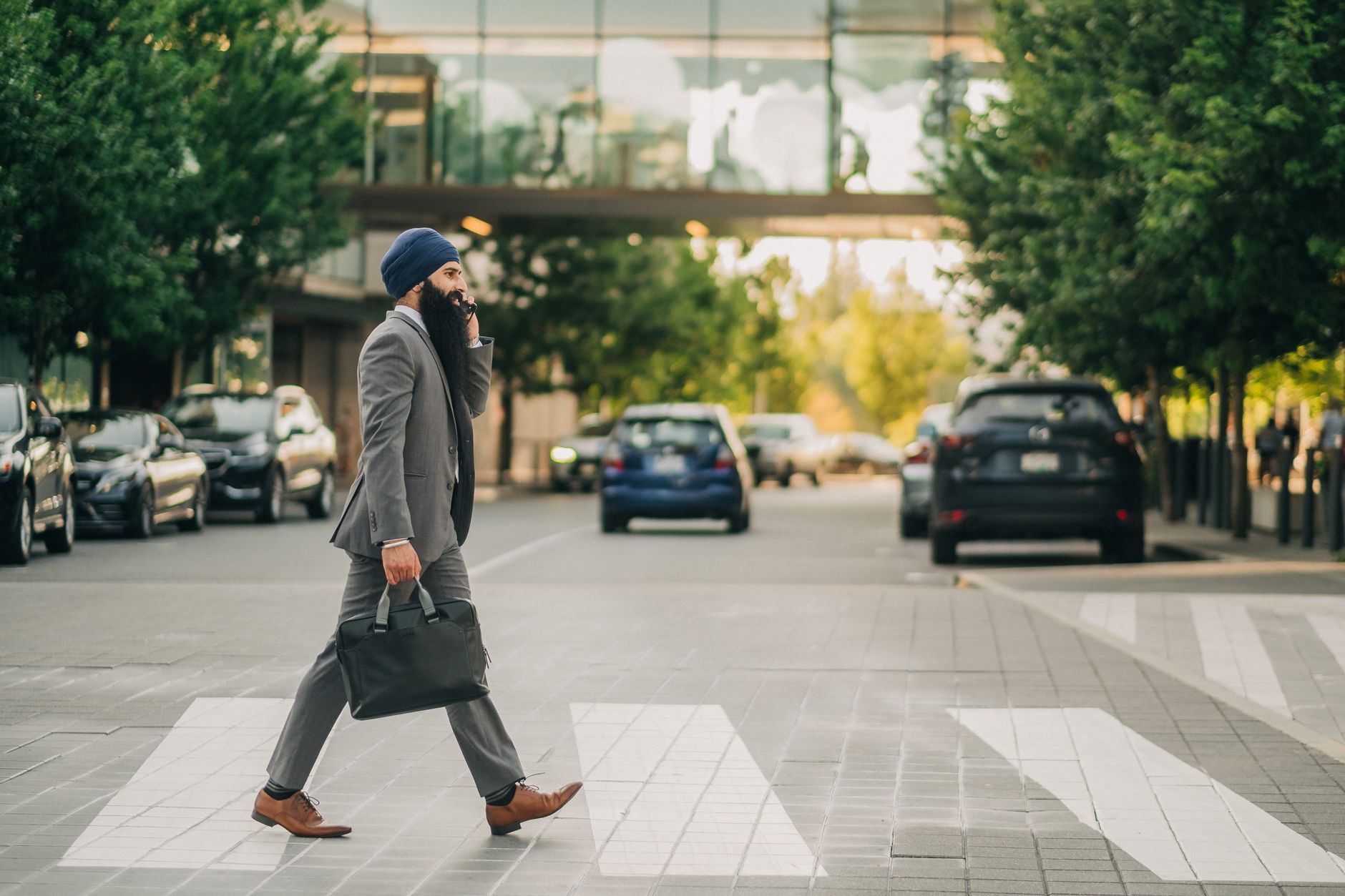 Sikh businessman with a turban crossing a city street on a zebra crossing, carrying a briefcase. — Elevating the Barcelona Ex