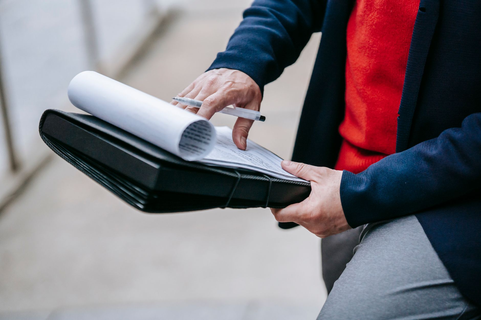 Close-up of a professional person reviewing documents outdoors. Engaged in work with focus on writing materials. — Gain Inter