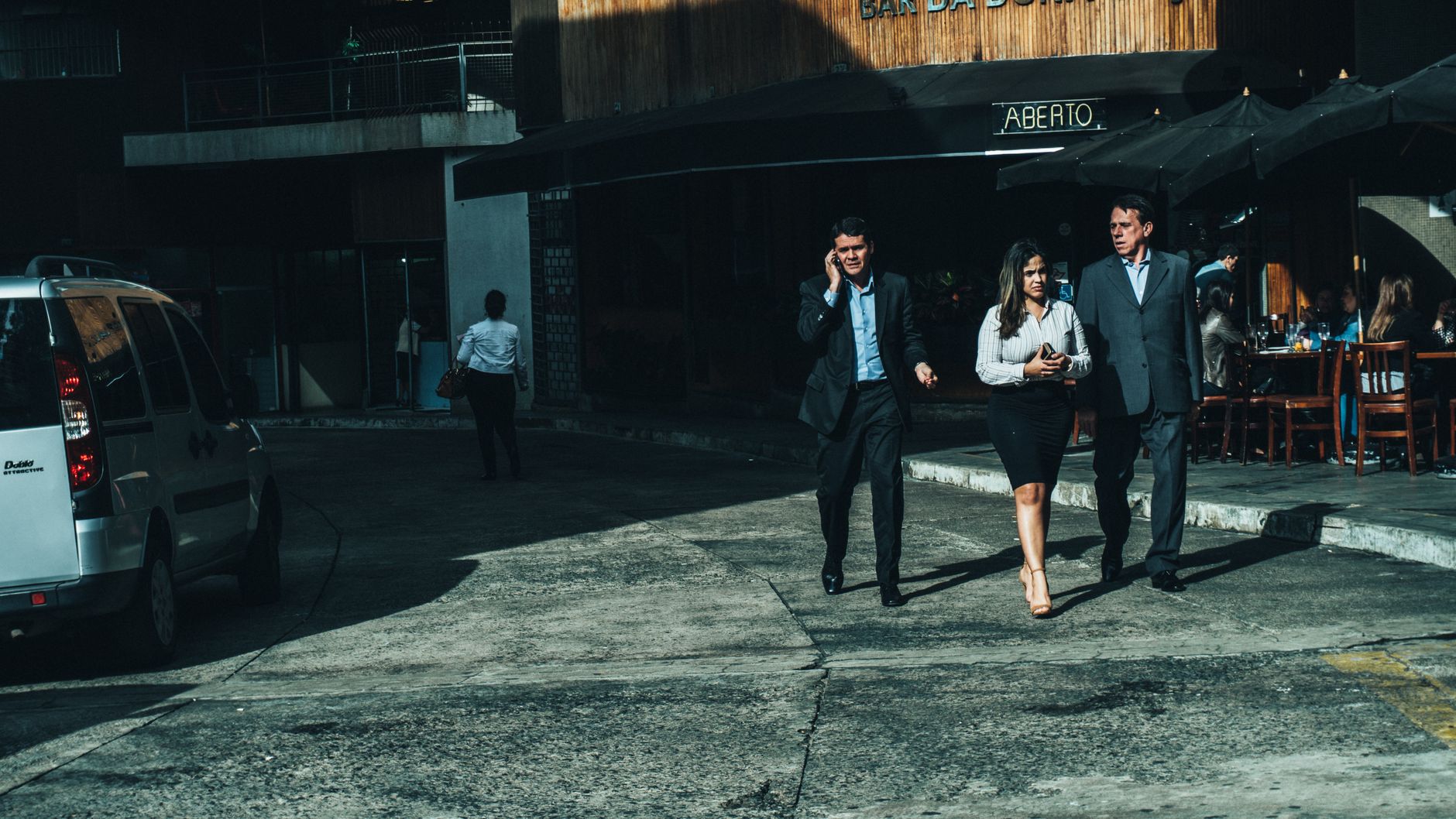 Three business professionals walk along a city street outside a cafe. — Get What You Need With an Impressive Looking Fake ID