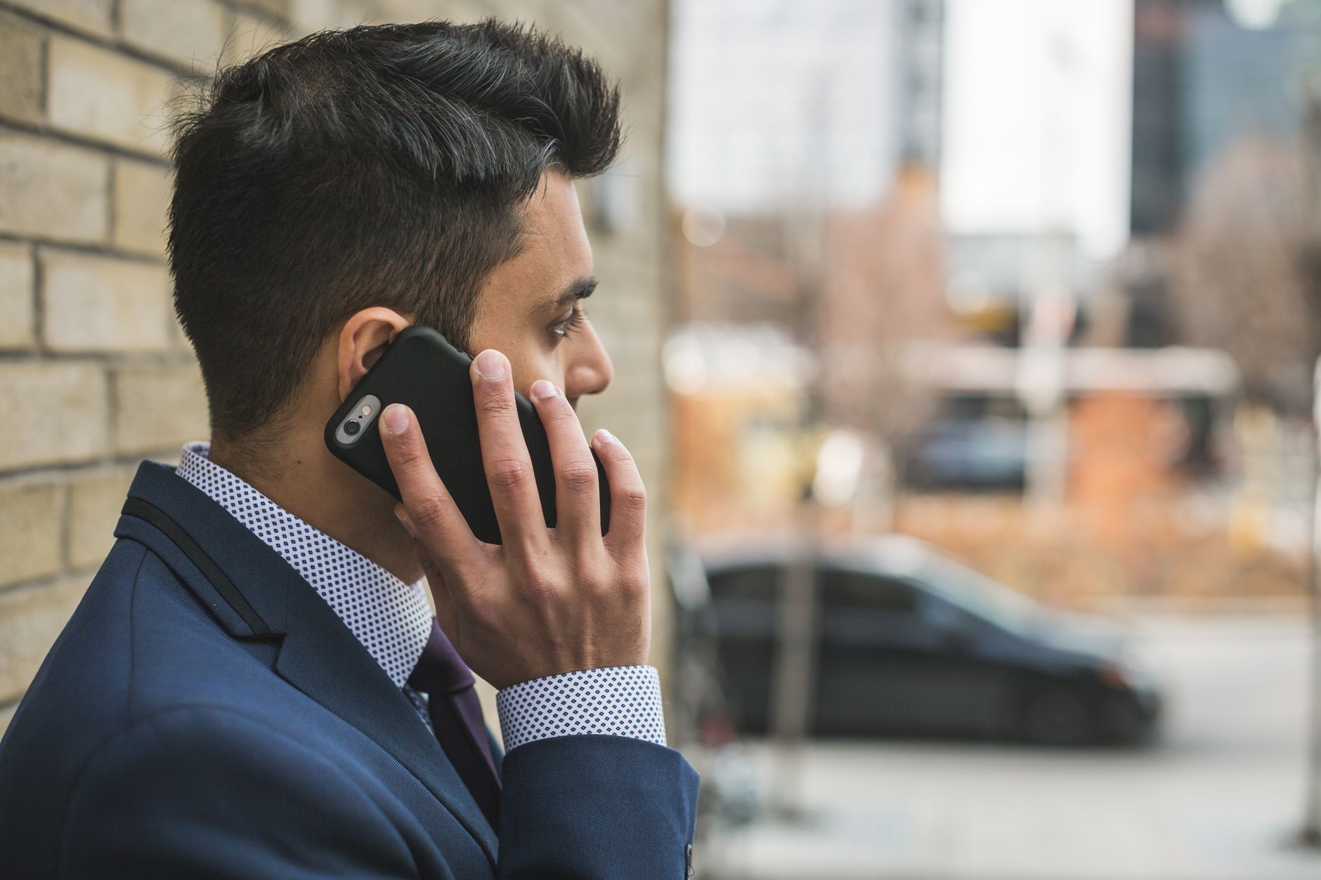 Professional man in suit making a phone call outside in city setting. — How to Market Your Pearls Jewelry around Customer Lif