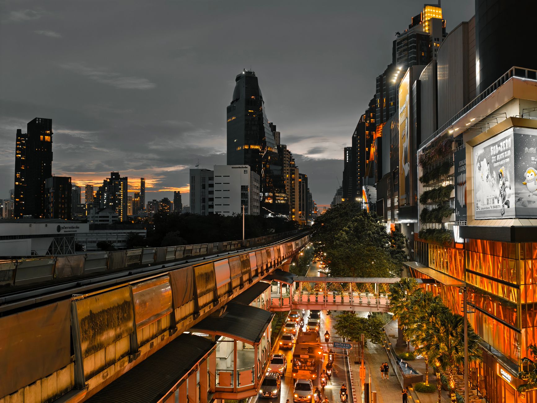 Cityscape at twilight showing busy traffic, skyscrapers, and an elevated train line in an urban setting. — Looking for luxuri