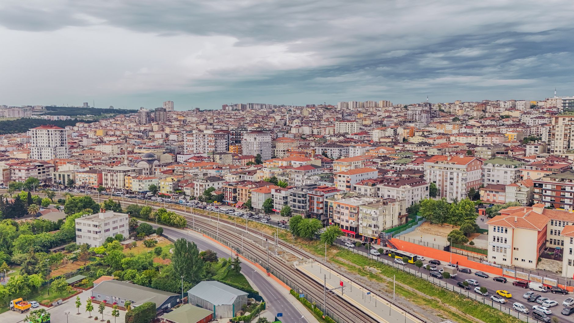 Aerial view of dense urban architecture with roads and greenery under cloudy skies. — Reap the Benefits of Cost-Effec