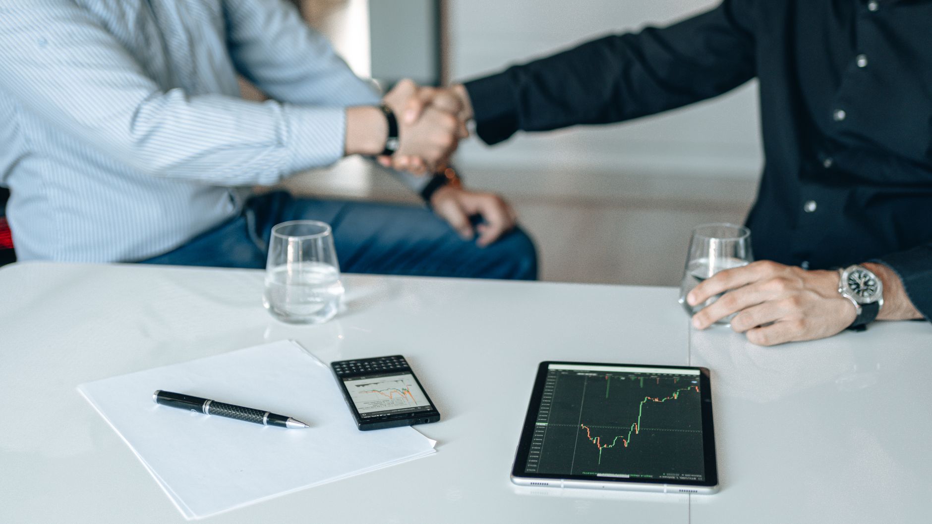 Business meeting with handshake and financial analysis displayed on a tablet. — Top Tips For Logistics Companies And Freight