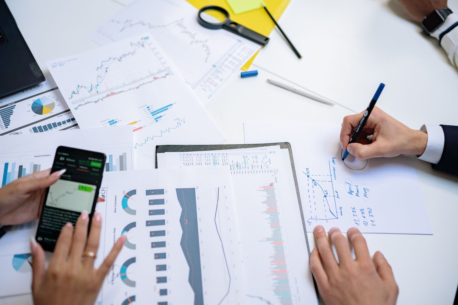 Colleagues collaborating on financial charts and graphs using mobile and paper documents in the office. — What is forex tradi